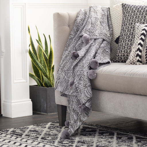 Knitted throw with online pom poms